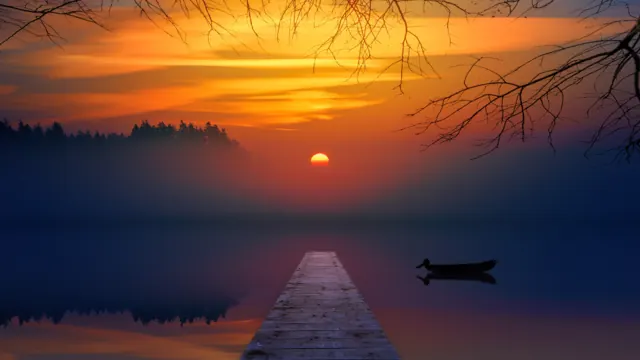 Wooden pier and a small boat on a lake at sunrise